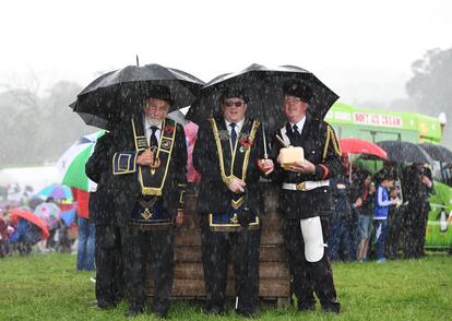 Miembros del 'Orange Order' y el 'Royal black Preceptory' de pie bajo la lluvia mientras miles de espectadores y manifestantes ven la pelea anual 'Sham Fight' en Scarva, Belgast, Irlanda del Norte.