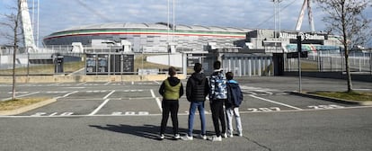 Cuatro jóvenes observan el Allianz Stadium tras la cancelación de varios partidos de la Serie A por el virus, en Turín, Italia.