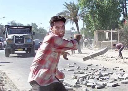 Un iraquí lanza una piedra contra un control estadounidense en Bagdad, ayer durante una protesta de ex policías.