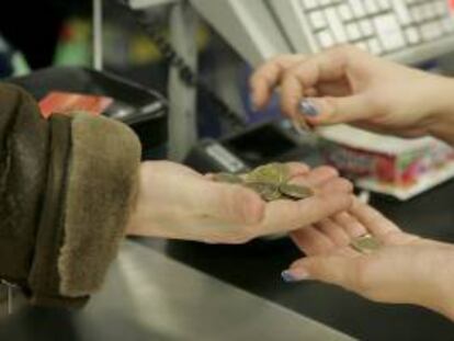 Una cajera ayuda a un cliente a contar las monedas de euro en un supermercado. EFE/Archivo