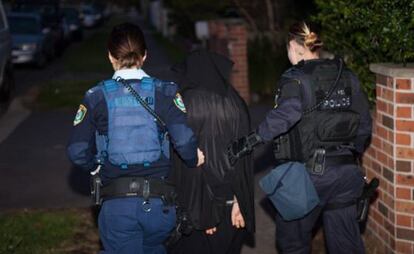 Dos policías acompañas a uno de los arrestados.