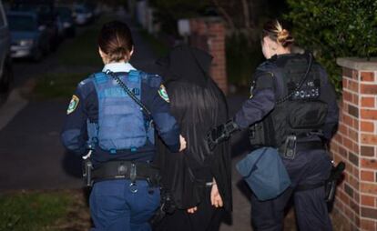 Dos polic&iacute;as acompa&ntilde;as a uno de los arrestados.