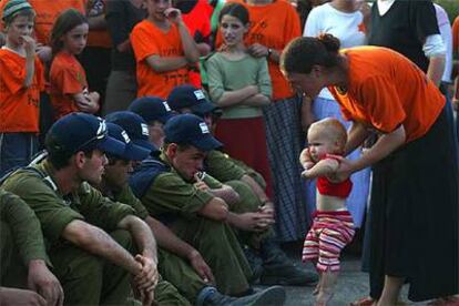 Una colona muestra a su hijo a los soldados israelíes encargados de desalojar el asentamiento de Neve Dekalim.