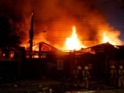 Los bomberos tratan de apagar el fuego en un almacén incendiado durante los disturbios en Chile.