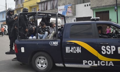 Oficiales del Grupo de Operaciones Especiales de la policía (GOPES) llevan a varios sospechosos detenidos en una furgoneta.