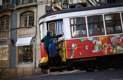 Dos jóvenes en el exterior de unos de los tranvías en la ciudad de Lisboa (Portugal).