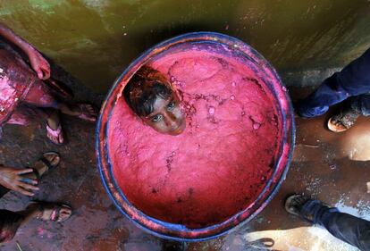 Un niño en el interior de un contenedor de plástico lleno de polvos de colores en la ciudad de Chennai (India).