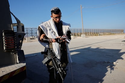 Un soldado israelí armado reza junto a un tanque, en el paso de Kerem Shalom, al sur de Israel, este lunes.