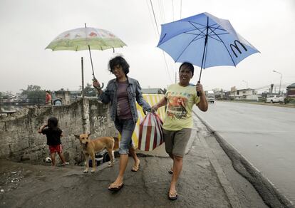 Dos mujeres evacuadas cargan con sus pertenencias en ciudad Paranaque, al sur de Manila. A su paso, Hagupit, ha provocado más de un millón de desplazados y al menos 21 fallecidos.