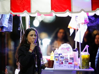 Una mujer fuma junto a un puesto de comida callejera, en Monterrey, Estado de Nuevo León, el 14 de enero de 2023.