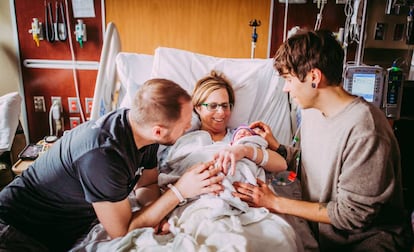 Cecile Eledge, após dar à luz Uma, entre seu filho Matthew (esq.) e o marido dele, Elliot.