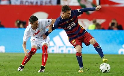El delantero argentino del FC Barcelona Lionel Messi (d) pelea un balón con el defensa del Sevilla Sergio Escudero.