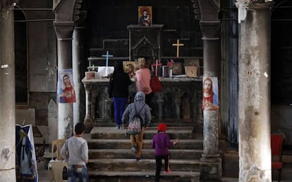 Cristianos iraquíes rezan en el altar de la iglesia de Qaraqosh, destruida durante su ocupación por parte del Estado Islámico.