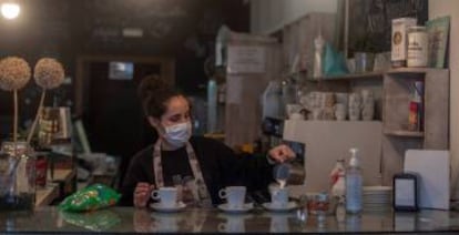 Una camarera sirve cafés en un bar. 