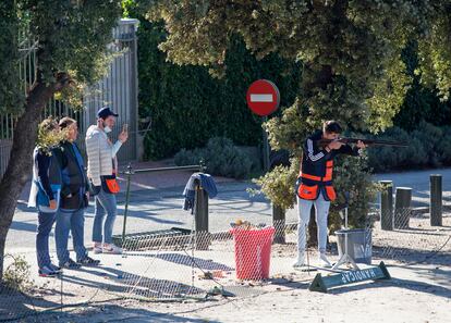 Unos competidores en el campeonato del tiro al pichón hacen práctica en una cancha con vista a la calle del Club de Tiro de Somontes en El Pardo.