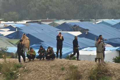 Personas observando a los migrantes abandonar el campamento de Calais (Francia). 