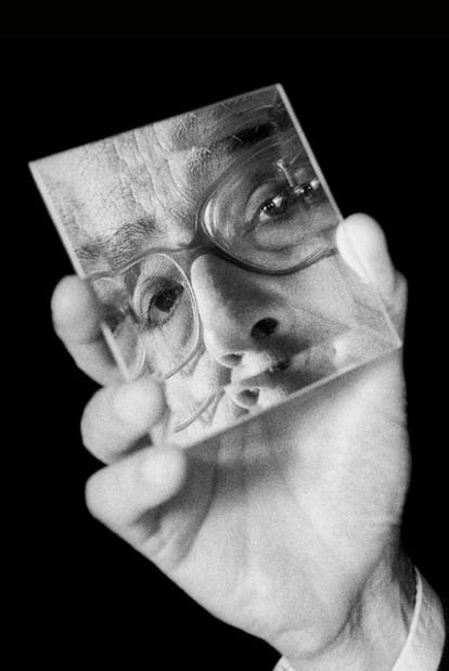 La mano de José Saramago sostiene un espejo en el que se refleja su rostro.
