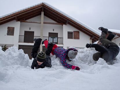 Tres niños se divierten en la nieve caída en Espinal (Navarra).