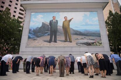 La gente se inclina ante un retrato de los difuntos líderes norcoreanos Kim Il Sung y Kim Jong Il, en el cruce de Dongmun en el distrito de Daedonggang de Pyongyang con motivo del 27º aniversario de la muerte de Kim Il Sung.