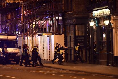 Un grupo de policías armados inspecciona un edificio cerca del puente de Londres.