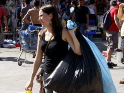 Una joven ayuda a los servicios de limpieza a recoger algunos restos tras la acampada de Sol.