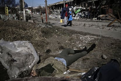 Civiles evacuan la ciudad de Irpin, frente a dos cuerpos de soldados rusos, en Irpin. El presidente ucranio, Volodímir Zelenski, ha afirmado este jueves que 60.000 personas han huido a través de los corredores humanitarios en las últimas jornadas.