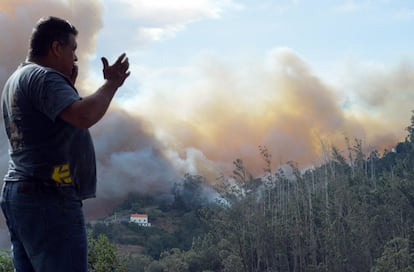 Homem fala por telefone enquanto observa como o fogo se aproxima das casas de Curral dos Romeiros, perto de Funchal.