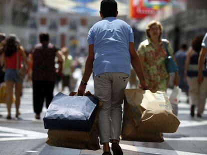 Un viandante con varias bolsas de compra (Zara, Springfield, etc) en la calle Preciados de Madrid.