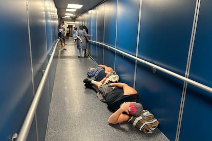 Viajeros en el Aeropuerto Internacional de Los Ángeles duermen en una pasarela para un vuelo retrasado de United Airlines.