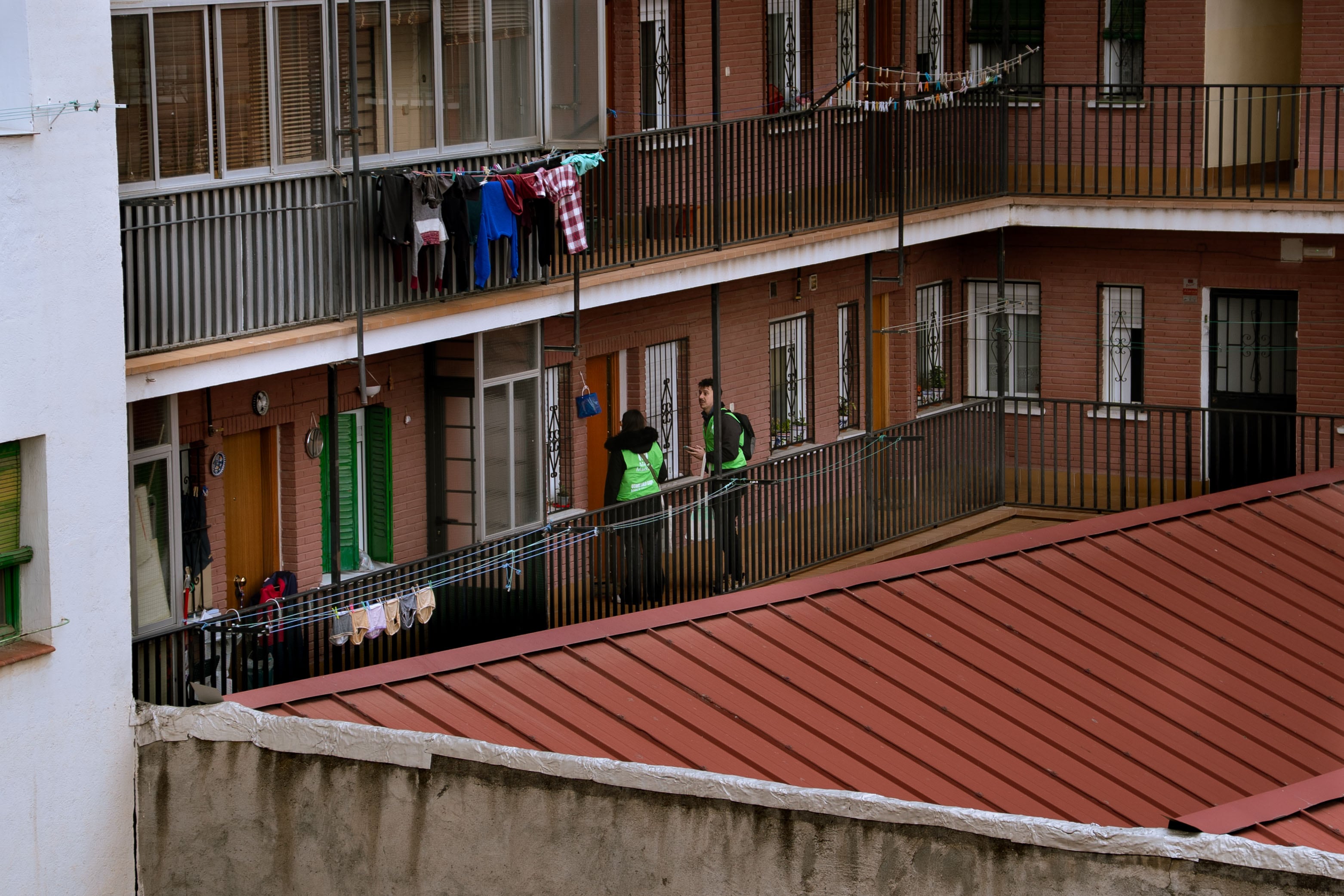 Dos voluntarios de Más Madrid ante una de las puertas que les han sido asignadas, en el distrito madrileño de Arganzuela este sábado.