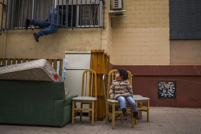 Após ser despejada com sua família, uma criança sentada junto a seus pertences observa um ativista defensor do direito à moradia tentar reabrir seu apartamento em Madri.