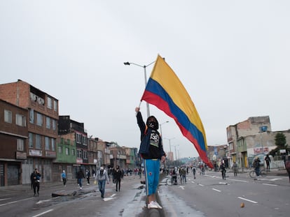 Un manifestante agita la bandera colombiana durante los enfrentamientos con la policía antidisturbios en una protesta contra el proyecto de ley de reforma tributaria propuesto por el Gobierno