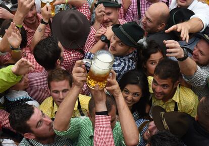 Visitantes del festival de la cerveza Oktoberfest en Múnich intentan tomar una jarra de cerveza justo después de la apertura del festival.