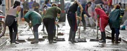 Vecinos de la barriada de Coca de la Piñera, en Utrera (Sevilla), limpian de lodo las calles.