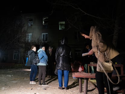 People stand outside a three-story apartment building in Kharkiv damaged by a Russian drone strike on April 4, 2024 .