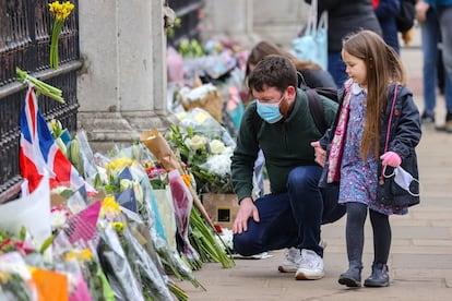 Un padre con sus hijas observa los ramos de flores frente al palacio de Buckingham en Londres, este sábado. Desde el anuncio de su muerte, se multiplicaron los mensajes de condolencias del mundo entero mientras el público se acercaba a los palacios de Windsor o Buckingham, residencia oficial de la reina en Londres, para depositar mensajes y flores.