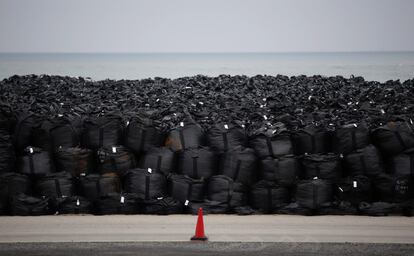 El objetivo es enterrar la tierra extraída durante las labores de descontaminación en una zona de 16 kilómetros cuadrados en los pueblos de Okuma y Futaba, aunque el Ejecutivo aún no ha podido adquirir todos los terrenos porque muchos de sus más de 2.000 propietarios recelan de que el depósito sea temporal y se niegan a vender. En la imagen, tierra contaminada por la radiación, hojas y otros residuos recogidos durante los trabajos de descontaminación se almacenan en grandes bolsas de plástico negras en una playa cercana a Fukushima.