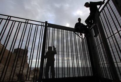 Jóvenes marroquíes, en la verja del espigón de melilla.