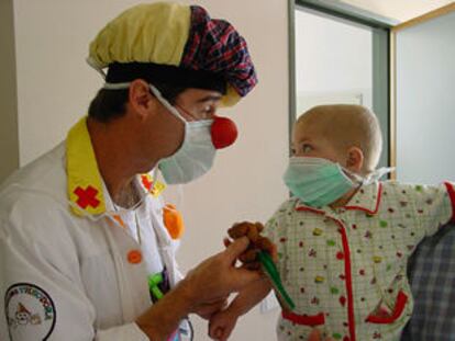 Uno de los payasos del programa Doctor Sonrisa juega con un niño ingresado en La Paz.