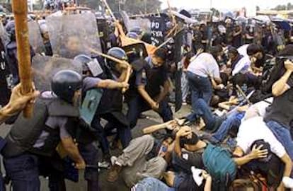 Varios policías se enfrentan a los manifestantes que protestaban, ayer en las calles de Manila, contra la política de la presidenta Gloria Macapagal.