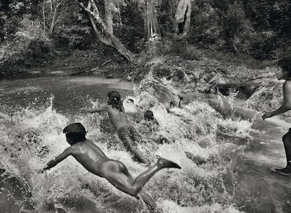 Crianças awá desfrutando das águas do rio Caru. Os adultos utilizam materiais da selva para a construção de moradias familiares.