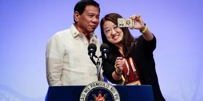 El presidente filipino Rodrigo Duterte sonríe mientras se hace un 'selfie' con una reportera china.