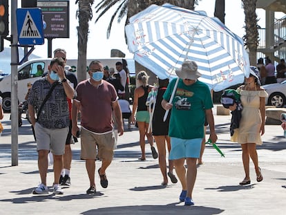 Un hombre se protege del intenso calor con una sombrilla de playa por las calles de la ciudad de Alicante a mediados del pasado julio.