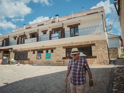 Un hombre camina frente al hostal de Griegos (Teruel) ofertado para atraer familias a la localidad.