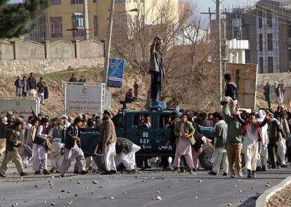 Manifestantes se apoderan de un vehículo policial durante un acto de protesta por la presunta quema de ejemplares del Corán en una base de la OTAN, en Herat, Afganistán.
