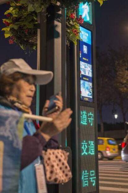 Una mujer asistente de tráfico junto a uno de los nuevos semáforos de reconocimiento facial.