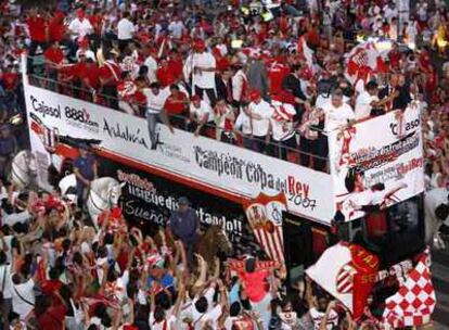 La plantilla del Sevilla, subida en un autobús, celebra con la afición el título de Copa.