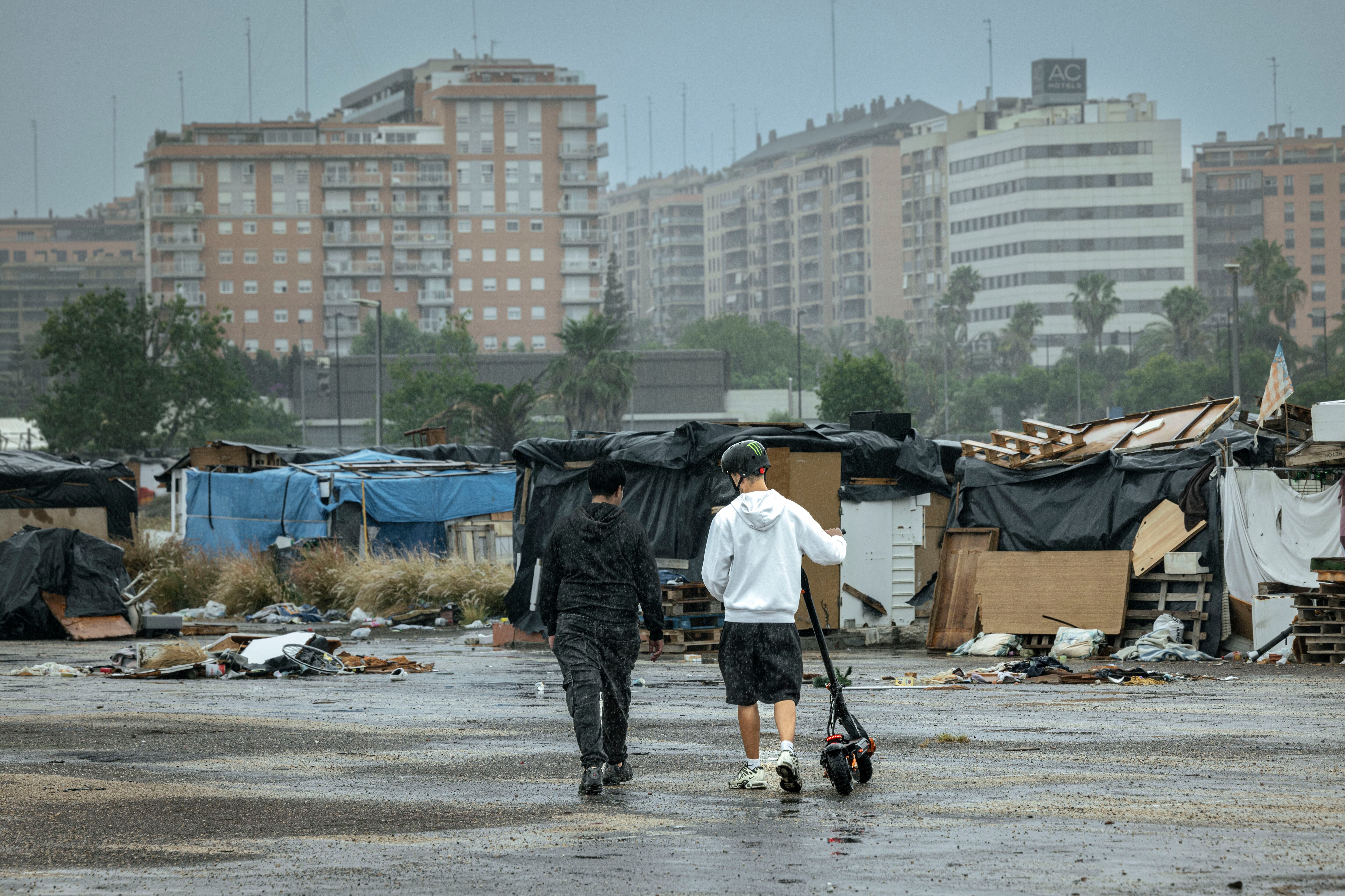 Dos jóvenes cruzan por el asentamiento chabolista en el antiguo circuito de Fórmula 1 de Valencia, este viernes.