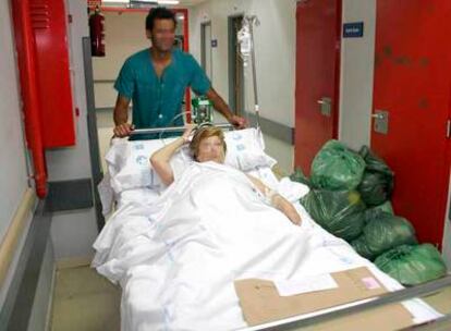 Una enferma es trasladada por uno de los pasillos del Hospital de la Paz, junto a un cúmulo de residuos.