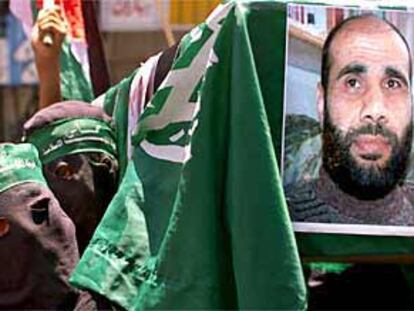 Dos militantes enmascarados de Hamás portan un retrato de Jamal Mansur, un dirigente de esa organización muerto en el ataque israelí.